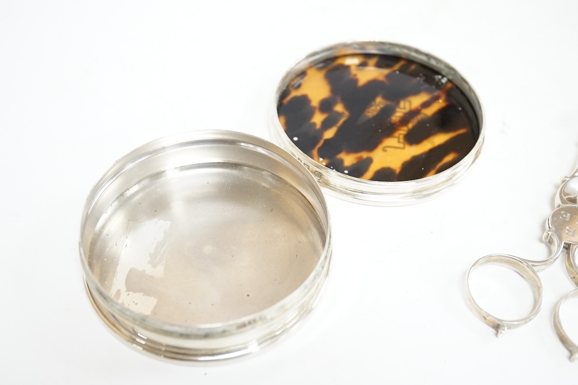A George V silver and tortoiseshell pique mounted circular trinket box, Collett & Anderson, London, 1922, diameter 77mm, together with a pair of 18th century silver sugar nips and a sterling mounted pin cushion, decorate